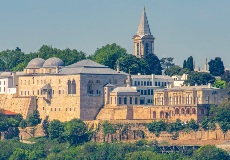 Panorama Pałacu Topkapi w Stambule z widocznymi kopułami, wieżą i zabudowaniami otoczonymi zielenią, położonego nad Bosforem